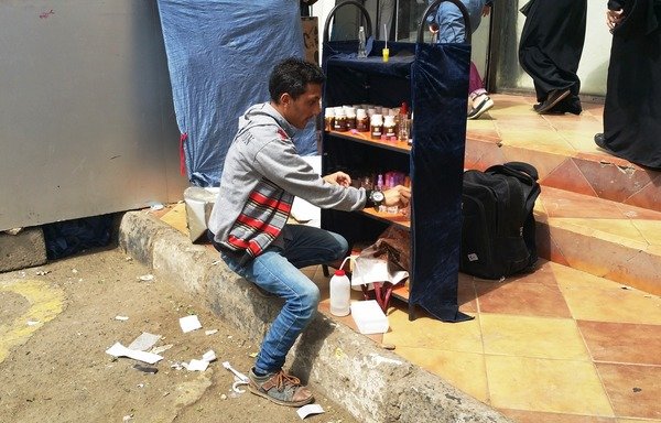 Khaled Shehab, 23, sells perfume from a stall in Sanaa. He and his family recently returned from Dhamar province, where they had fled Yemen's war. [Faisal Darem/Al-Shorfa]