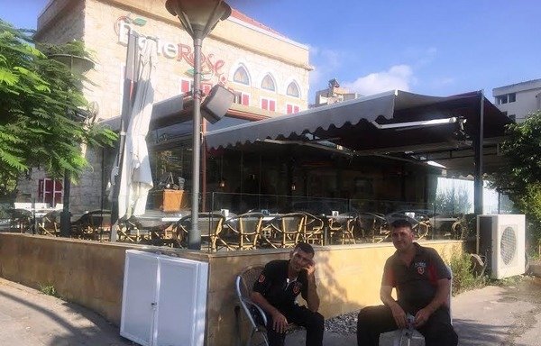 دو کارگر یک رستوران در آتلیاس، بیروت بیرون رستوران منتظر مشتری نشسته اند. بخش گردشگری در اثر حملات تروریستی گروههای افراطی و جنگ در سوریه دچار بحران شده است. [نهاد طوبالیان/ المشارق]