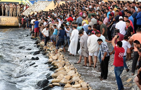 مصريون على الشاطئ بانتظار انتشال جثث الذين غرقوا بحادثة انقلاب سفينة للمهاجرين في البحر المتوسط على طول الشاطئ المصري عند مدينة رشيد في 22 أيلول/سبتمبر 2016. [محمد الشاهد/أ ف ب]