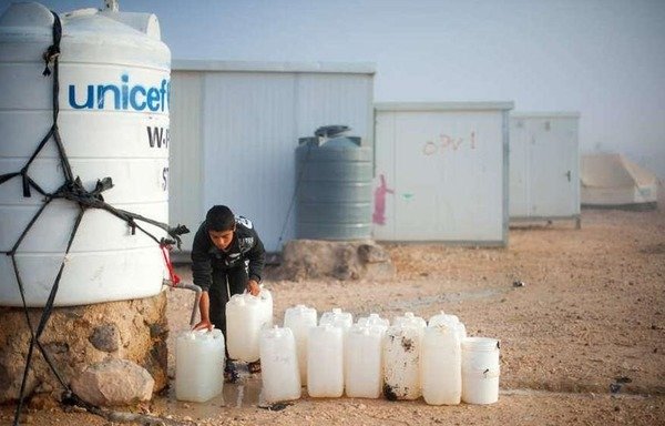 A Syrian boy fills water jugs in Jordan's sprawling Zaatari refugee camp. [Photo courtesy of UNHCR Jordan]