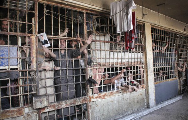 Inmates reach through the bars at Saydnaya prison in Syria. An Amnesty International report revealed the Syrian regime has executed 13,000 detainees since 2011. [Photo from the archive of Bashir al-Bassam]