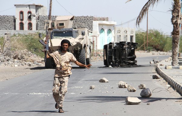 A fighter loyal to Yemeni President Abd Rabbu Mansour Hadi raises his weapon in front of the wreckage of a car in the Red Sea port of Mokha as Yemeni forces advance on the Houthis on February 11th. [Saleh al-Obeidi/AFP]
