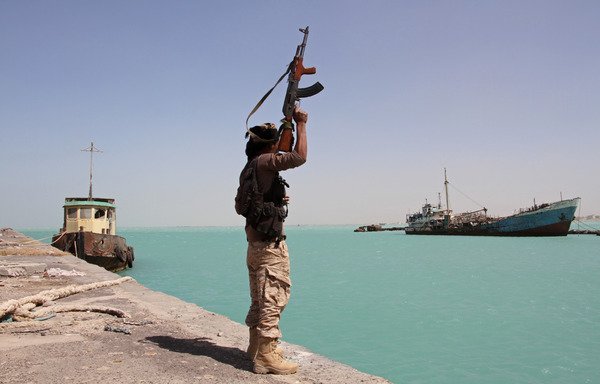 A member of the forces fighting in support of Yemeni President Abd Rabbu Mansour Hadi raises his weapon in the Red Sea port of Mokha on February 9th. Yemeni forces, backed by the coalition, began a major offensive on January 7th to recapture the coastline overlooking the strategic Bab al-Mandab Strait. [Saleh al-Obeidi/AFP]