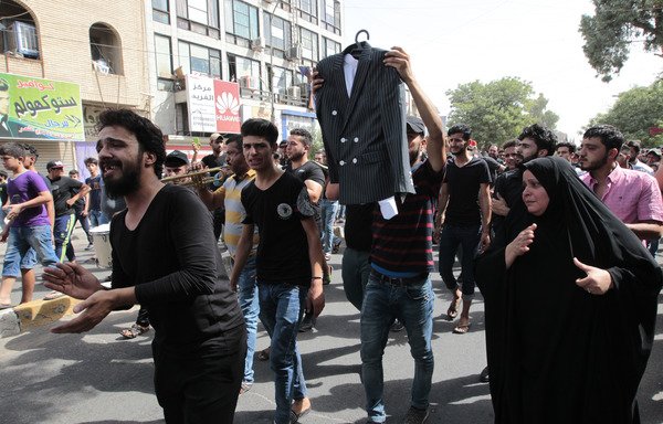 Mourners hold the wedding suit of Akram al-Karradi, a 22-year-old victim of a suicide bombing that ripped through Baghdad's busy shopping district of Karrada two days earlier, during his funeral on July 5th, 2016. The suicide bombing claimed by the 'Islamic State of Iraq and the Levant' killed more than 200 people. [Sabah Arar/AFP]