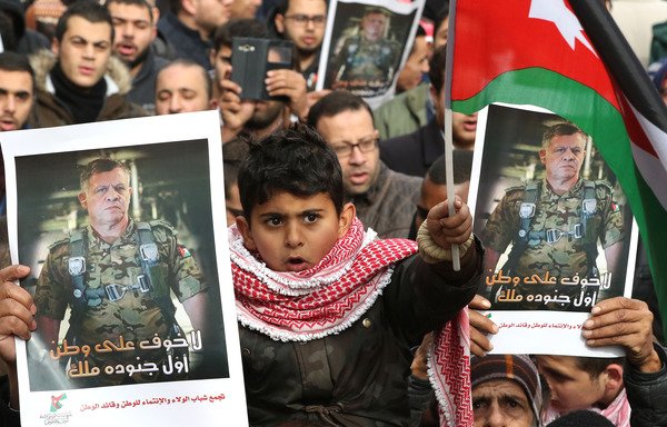 A child waving Jordan's national flag joins protesters holding posters of King Abdullah during a December 23rd rally in Amman to support security services after an attack in Karak. Participants at a recent forum in Amman explored ways to boost constructive youth engagement to prevent marginalisation, a leading cause of extremism. [Khalil Mazraawi/AFP]