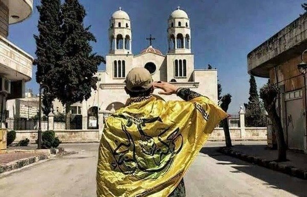 An Iraqi fighter from the IRGC-backed Harakat al-Nujaba stands in front of a church in the Hama province town of Maharda. [Photo from the Shams Maharda Facebook page]