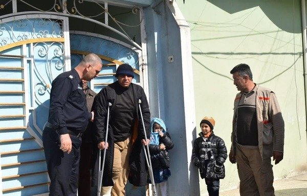 An Iraqi officer assists a man on crutches in Mosul. Iraqi officials say the 'Islamic State of Iraq and the Levant' has preyed on the mentally ill, the physically disabled and children, to use them as human shields or suicide bombers. [Photo courtesy of Ninawa Information Centre]