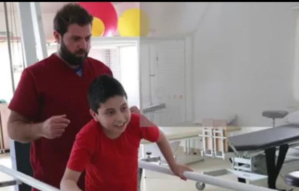 Syrian child Ahmad, who lost his lower limbs during the war in Aleppo, underwent reconstructive surgery at the Rafiq Hariri Hospital in Beirut. In the photo, Ahmad is undergoing rehabilitation with the help of an ICRC therapist to practice walking with his prosthetic legs. [Photo courtesy of ICRC Lebanon]