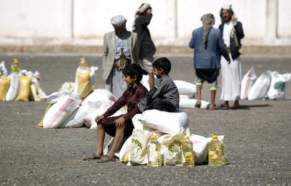 Yemeni boys sit on a food aid bag distributed by a local charity in Sanaa during Ramadan on June 7th. [Mohammed Huwais/AFP]