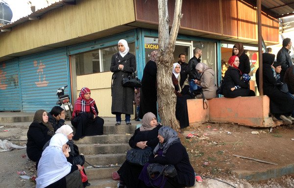Syrians wait for the arrival of a convoy carrying their relatives near al-Masnaa border crossing on December 28th. [Hasan Jarrah/AFP]