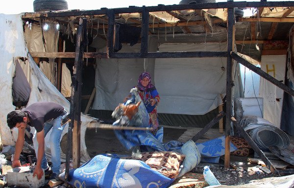Syrian refugees clear up the damage after a fire engulfed part of the Tel al-Sarhoun refugee camp near the Bekaa Valley town of Bar Elias on July 4th. [Hassan Jarrah/AFP]