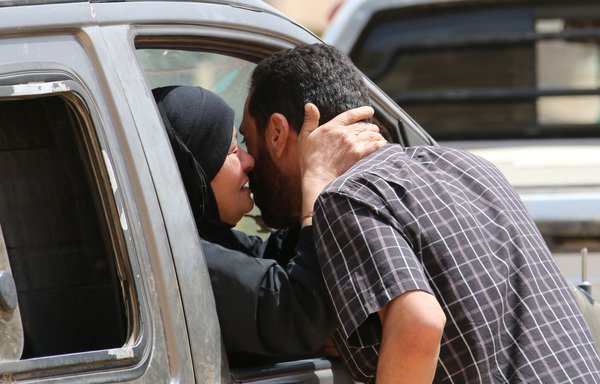 لاجئ سوري يُقبل إحدى قريباته بينما تجلس بداخل سيارة في مدينة عرسال الحدودية بشرق لبنان في طريقها إلى منطقة القلمون السورية يوم 12 تموز/يوليو [صحافي مستقل/أ ف ب]