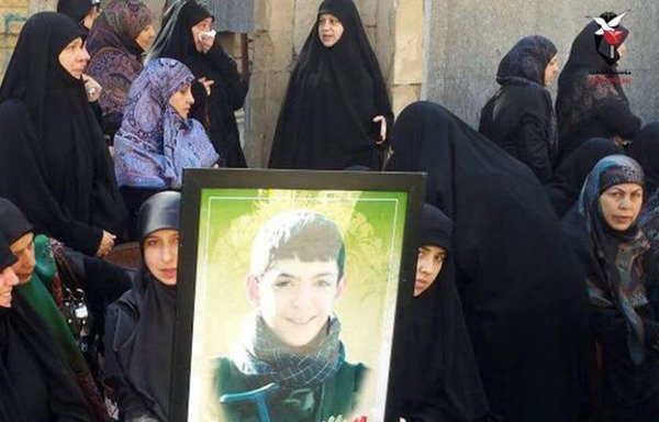 Shia women hold a photograph of teenager Mahdi Hassan Abu Hamdan, a Hizbullah recruit killed in Syria.  [Photo via Hizbullah-affiliated Sada al-Shohada Facebook page]