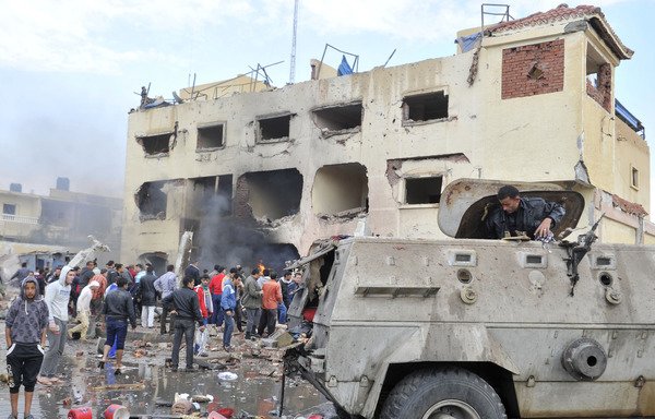 An Egyptian man stands in an armoured vehicle as residents gather outside a police station in North Sinai's provincial capital of el-Arish after it was targeted by a car bomb on April 12th, 2015. [Stringer/AFP]
