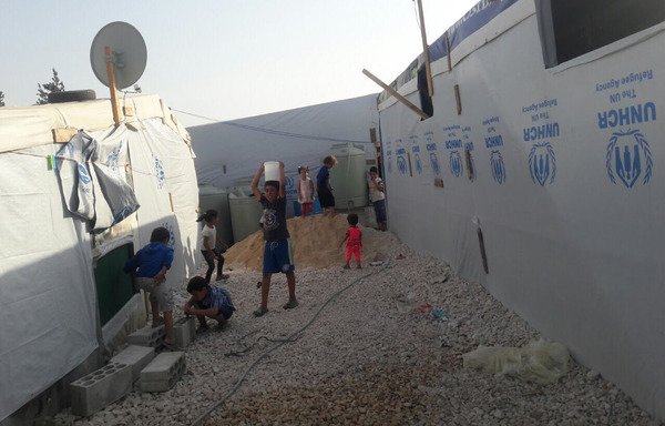 أطفال من اللاجئين السوريين يلعبون قرب خيم جديدة أقامتها منظمات محلية ودولية بعد أن دمرت الحرائق أكثر من 200 خيمة في مخيمين في منطقة البقاع. [نهاد طوباليان/المشارق]