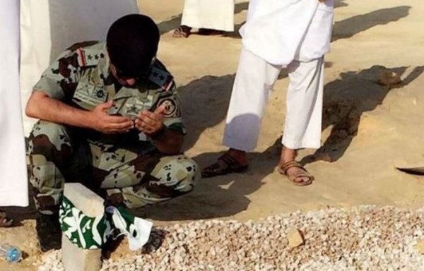 A Saudi security officer prays over the grave of a police officer killed in an attack in the town of Awamiya. [Photo circulated on the social media sites of Saudi activists]