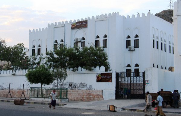 A picture taken on May 3rd, 2016, shows people walking past an Islamic charity council building in the Yemeni port of al-Mukalla, in Hadramaut. The government is inaugurating new service projects in the province this week. [Stringer/AFP]