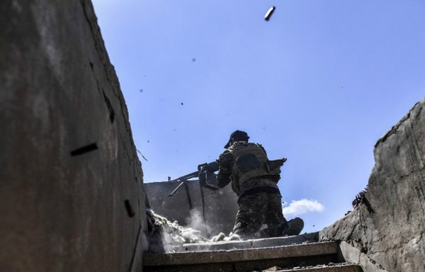 A member of the Syrian Democratic Forces (SDF) fires his machine gun during clashes with 'Islamic State of Iraq and Syria' extremists near the central hospital of al-Raqa on October 1st. Syrian fighters are battling to clear the last remaining ISIS fighters holed up in their crumbling stronghold of al-Raqa. [Bulent Kilic/AFP]