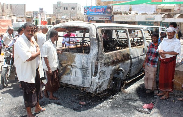 Yemenis gather around a burnt vehicle at the site where a mine, that Yemeni soldiers were taking away in their vehicle, blew up in a marketplace on September 3rd, 2016 in Lahj province, where al-Qaeda has a presence. [Saleh al-Obeidi/AFP]