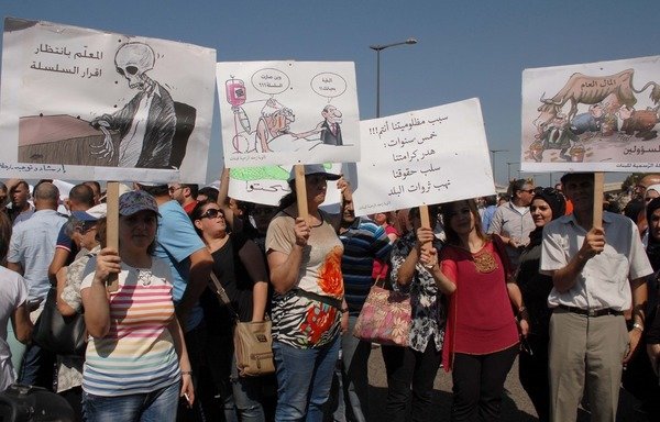 Lebanese citizens stage a protest to call for parliament to approve a law that will increase public sector employees' salaries. The law was approved by parliament in July. [Al-Mashareq]