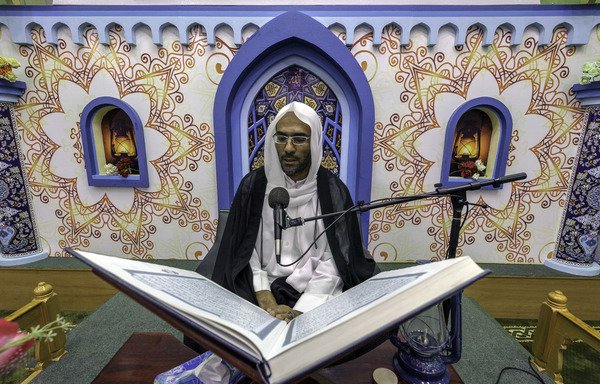 رجل دين سعودي يتلو آيات من القرآن الكريم في مسجد القطيف في أول أيام شهر رمضان المبارك الموافق في 27 آيار/مايو. عزّزت المملكة مراقبة الأئمة والدعاة، وأقالت مؤخراً الآلاف منهم بتهمة استغلال منصبهم للترويج للتطرّف. [حسين رضوان/وكالة الصحافة الفرنسية]