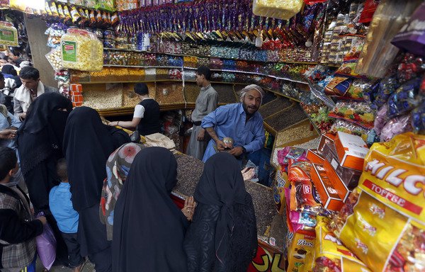 Yemenis buy sweets and nuts at a market in the capital Sanaa. The continued deterioration of the Yemeni riyal against foreign currencies threatens to undermine citizens' abilities, experts warn. [Mohammed Huwais/AFP]