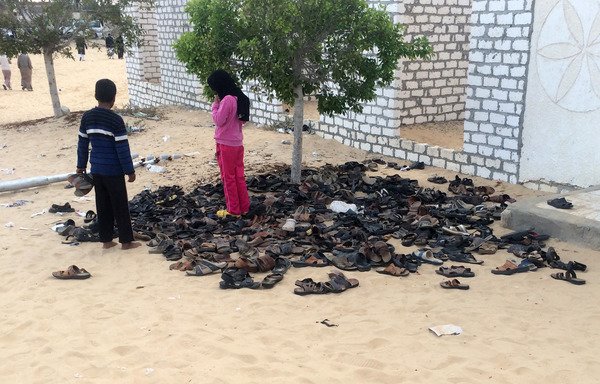 Egyptian children stand near a pile of footwear belonging to the victims of the attack that targeted the Rawda mosque near North Sinai provincial capital of al-Arish, on November 24th. [STR/AFP]