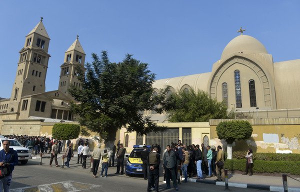 Egyptian security forces and onlookers gather outside the St. Peter and St. Paul Coptic Orthodox Church, which is adjacent to the Saint Mark's Coptic Orthodox Cathedral, after it was hit by an explosion on December 11th, 2016 in the Abbasiya neighbourhood in Cairo. [Khaled Desouki/AFP]