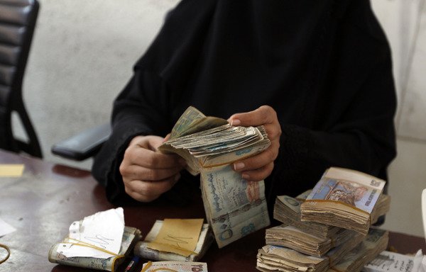 An employee counts stacks of Yemeni currency at the Central Bank of Yemen in Sanaa on August 25th, 2016. Yemen's currency has been in sharp decline since the Houthis seized control of the Central Bank. [Mohammed Huwais/AFP]