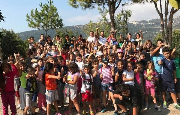 أطفال عراقيون كلدان مع أساتذتهم في صورة بعد نهاية نشاط أقيم لهم في مركز سيدة الرحمة الإلهية الرعوي في سد البوشرية. أفتتح المركز مؤخرا مدرسة ومركزا للتعليم المهني للأطفال الكلدان اللاجئين في لبنان. [حقوق الصورة لمركز سيدة الرحمة الإلهية الرعوي]