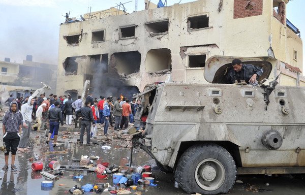 An Egyptian man stands in an armoured vehicle as residents gather outside a police station in North Sinai's provincial capital of al-Arish after it was targeted by a car bomb on April 12th, 2015. [Stringer/AFP]