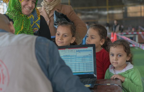 یک مادر پناهنده سوریه ای و فرزندش کارت مشترک را از یونیسف که از طریق آن کمکهای نقدی ارائه می شود را دریافت می کنند. [استفان جرارد کلی/یونیسف]