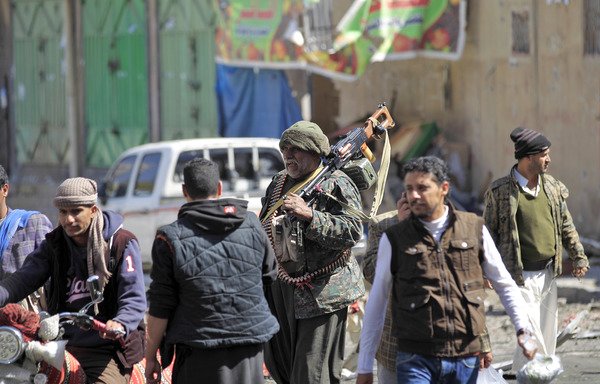 مقاتل حوثي يحمل رشاشا ثقيلا على كتفه وهو يسير في أحد شوارع صنعاء. [محمد حويس/وكالة الصحافة الفرنسية]