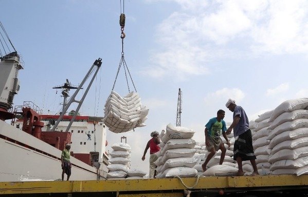 Workers unload wheat assistance provided by UNICEF from a cargo ship at the Red Sea port of al-Hodeida on January 27th. The Houthis (Ansarallah) have been accused of looting aid intended for impoverished Yemenis in areas under their control. [Abdo Hyder/AFP]