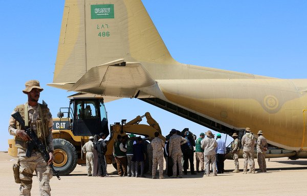 Saudi soldiers stand guard as workers unload aid from a Saudi air force cargo plane at an airfield in Yemen's Marib province on February 8th. [Abdullah al-Qadry/AFP]
