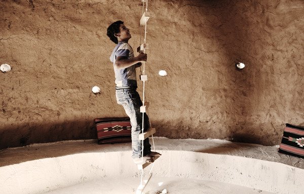 A child climbs a rope ladder inside a new beehive-style classroom in Zaatari village. [Photo courtesy of Martina Rubino/EAHR]