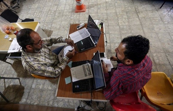 Iraqis renew their voting registry records at an electoral commission office in the Holy city of Najaf on March 10th. Iran is accused of trying to sway votes in the upcoming Iraqi elections towards pro-Tehran candidates. [Haidar Hamdani/AFP]