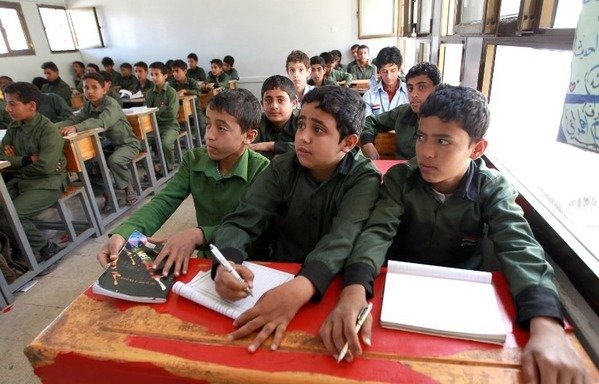 Yemeni schoolboys attend class in the capital Sanaa on February 8th, 2015, two days after the Houthis seized power dissolving the government and parliament. Three years later, the militia paused classes for a month replacing them with activities that aimed at brainwashing and recruiting children among its ranks. [Mohammed Huwais/AFP]