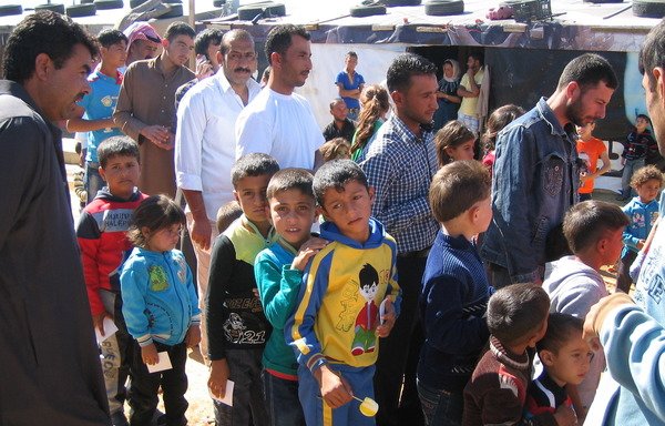 Syrian refugees line up to receive aid in the Zahle area of the Bekaa Valley. Refugees have strained Lebanon's infrastructure, but their presence also has boosted the economy, experts said. [Junaid Salman/Al-Mashareq]