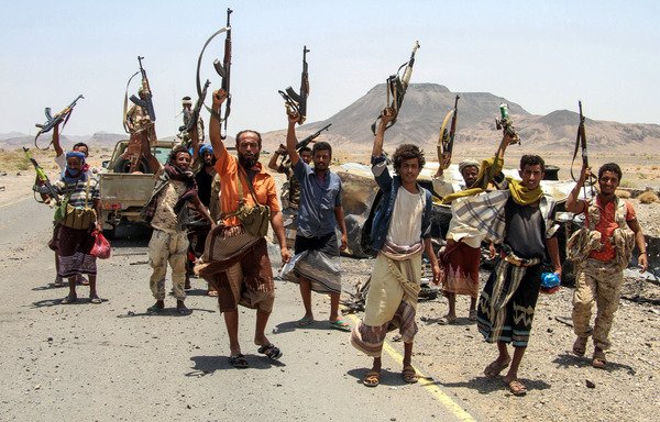 Yemeni fighters loyal to President Abd Rabbu Mansour Hadi raise their machine guns on April 15th, 2017, on the road leading to Khaled Ibn Al-Walid base, east of the Red Sea port of al-Mokha. The camp, one of the biggest in Yemen, sits on a key road linking al-Mokha to the Houthi-controlled port city of al-Hodeida and the city of Taez. [Saleh al-Obeidi/AFP]