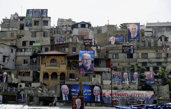 Posters of candidates for the upcoming Lebanese parliamentary elections hang on the walls of buildings in Tripoli's adjacent Bab al-Tabbaneh and Jabal Mohsen neighbourhoods on May 3rd. [Joseph Eid/AFP]