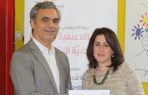 رئيس جامعة اللاعنف وحقوق الإنسان عصام منصور يقدم شهادة لأحد المشاركين. [حقوق الصورة لجامعة اللاعنف وحقوق الإنسان]