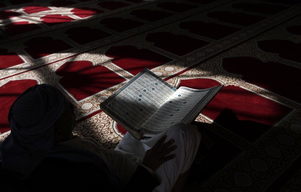 A Yemeni man reads the Qur'an at the Great Mosque in Sanaa's Old City on May 19th, during the holy month of Ramadan. [Mohammed Huwais/AFP]