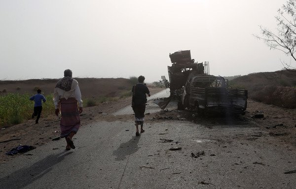 Yemenis check the wreckage of an armoured vehicle and a pick up truck after clashes between fighters loyal to President Abd Rabbu Mansour Hadi and Houthi militia fighters, near the coastal town of al-Hodeidah, on May 29th. [Abdo Hyder/AFP]