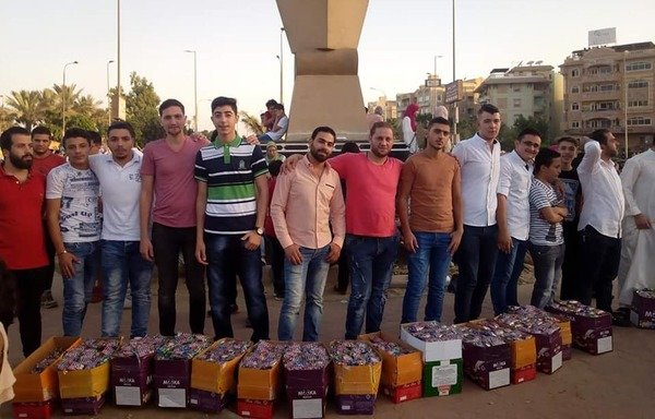 شباب سوريون يقدمون الحلوى للمارة في مدينة 6 أكتوبر في مصر خلال عيد الفطر. [حقوق الصورة لمحمد العبدالله]