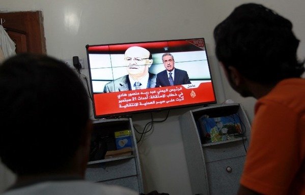 Young Yemenis in Sanaa watch a news channel as Yemeni leader Abd Rabbu Mansour Hadi is displayed on the screen in this archive photo from January 2015. [Mohammed Huwais/AFP]