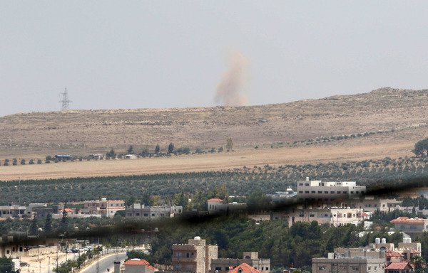 A picture taken on June 30th from the northern Jordanian city of Ramtha shows pillars of smoke rising across the border from Syrian regime shelling in the Daraa countryside. [Khalil Mazraawi/AFP]