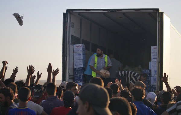 Displaced Syrians from Daraa province gather to receive aid food in a makeshift camp near the Jordanian border and the town of Nassib, southern Syria, on July 2nd. [Mohamad Abazeed/AFP]