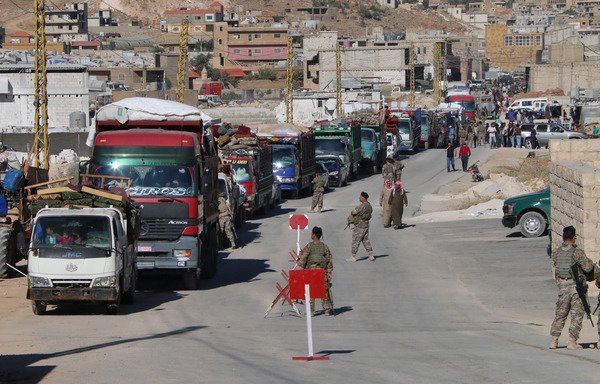 Lebanese soldiers at a checkpoint in Wadi Hmeid in the Bekaa Valley supervise a convoy transporting Syrian refugees who left Arsal to return to their homes in Syria's Qalamoun region on July 23rd. [AFP]