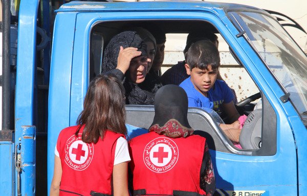 Lebanese Red Cross members speak to Syrian refugees at a Lebanese army checkpoint in Wadi Hmeid on July 23rd. [AFP]